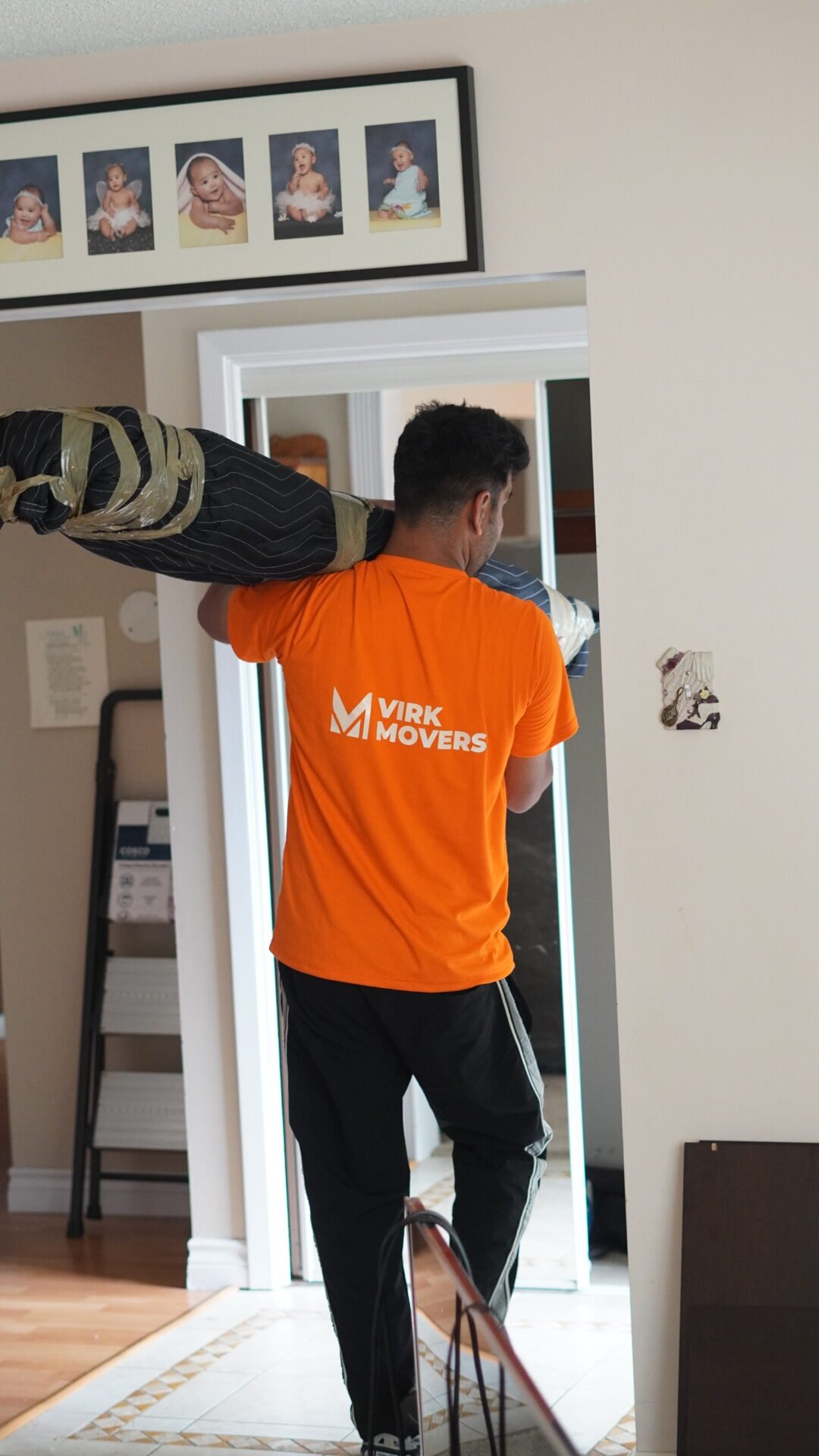 Virk Movers professional carrying furniture wrapped in protective moving blankets through a doorway during a residential move.